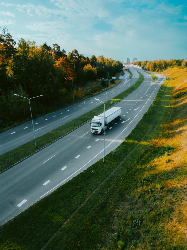 Top view of a truck driving along a highway road in evening time under a sunny blue sky